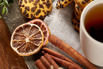 Traditional Christmas tea concept with a cup of hot tea, cookies and decorations on a wooden table, selective focus