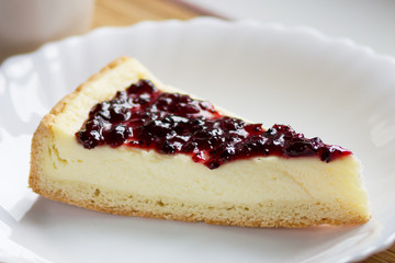 Dessert cake creme cheesecake with blueberry jam on a white plate