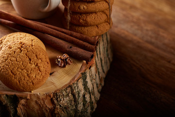 Christmas concept with a cup of hot tea, cookies and decorations on a log over wooden background, selective focus