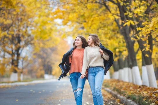 Young Pretty Girls Having Fun Outdoors In Autumn Background. Cheerful Friends In The Fall Time