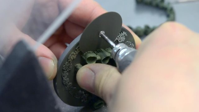 Man cuts the small saw of the detail from the working disk disk for 3d metal printer. Dental crowns created in laser sintering machine. DMLS, SLM, SLS additive technology. 4.0 industrial revolution