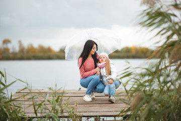 Fototapeta premium Young mother with her little daughter in the fall time near the lake