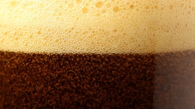 Close up of pouring dark beer with bubbles. No sound. This file is cleaned and retouched.