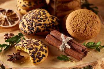 Sweet assortment of biscuits on a round wood log over rustic wooden background, close-up, selective focus.