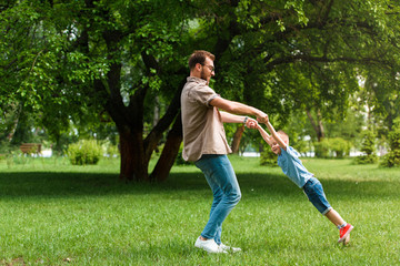 father spinning around son and they having fun at park