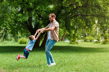 happy father spinning around son and they having fun at park