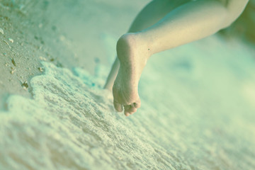 closed up barefeet walk alone on beach sand ocean water with foam