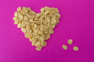 Cornflakes on a pink background in the form of a heart
