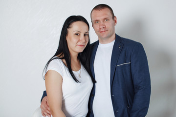 Picture of happy young loving couple standing over grey wall.
