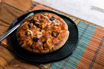 Sea food pizza in black plate on wooden table