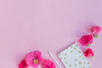 Flat lay desk with pink flowers and notebook