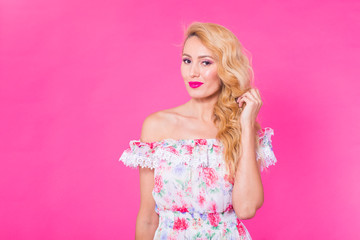 Beautiful girl wearing dress posing on pink background in studio with copyspace. Summer, holidays and fashion concept