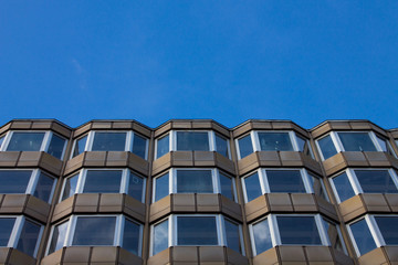 Modern architecture windows see from bottom with sky reflection. Windows pattern. Sky in background.