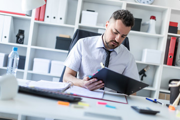 Fototapeta premium A man is sitting in the office and scrolls through the documents.