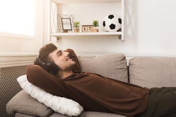 Young casual man in headphones at home