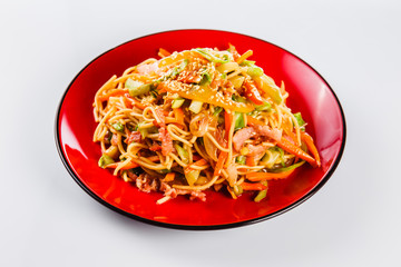 noodles with bacon, pepper and sesame seeds on a red plate on a white background. Traditional Italian pasta. Close