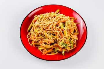 Noodles with pork, pepper and sesame seeds on a red plate on a white background. Traditional Italian pasta. Close