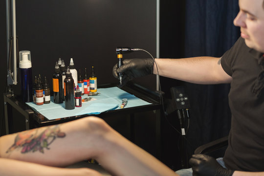 Professional tattoo artist making tattoo on leg