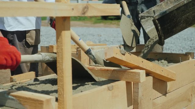Making a socle in a private house. Workers pour concrete into the wooden formwork