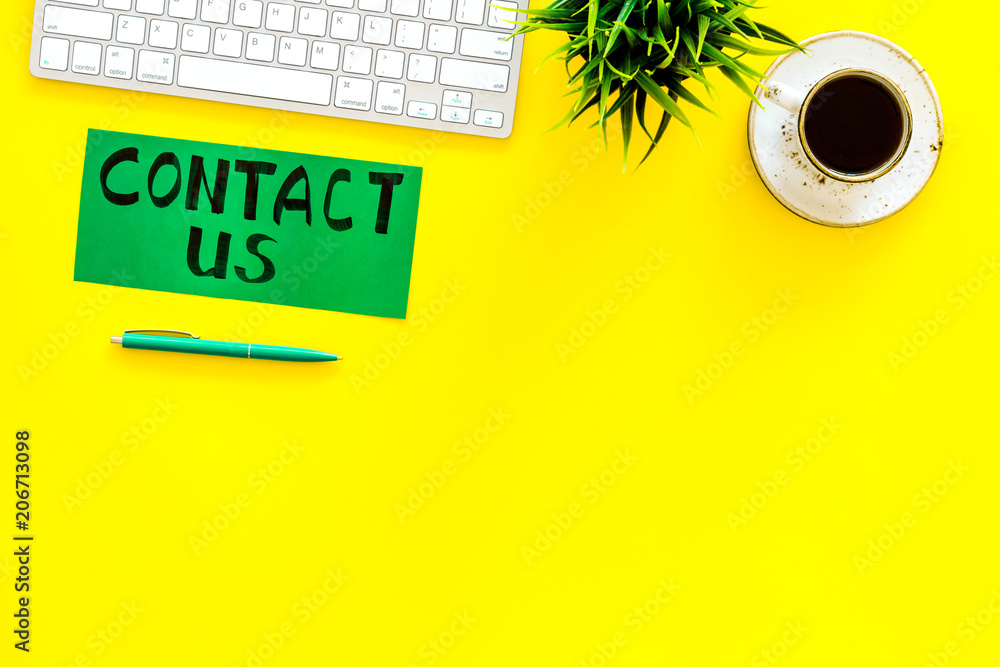Poster frame contact us. lettering contact us on office work desk with computer on yellow background top vi