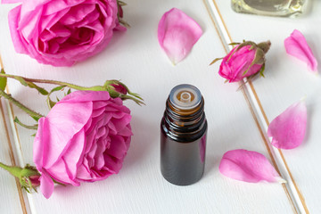A bottle of essential oil with fresh roses