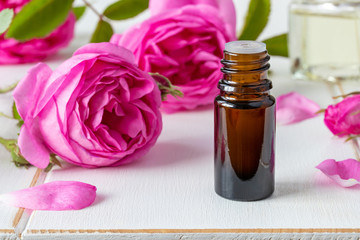 A bottle of essential oil with fresh roses