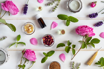 Bottles of essential oil with roses, peppermint, lavender and other herbs and flowers