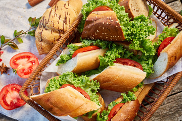 Picnic basket full with sandwiches, baguette and croissant on a homespun tablecloth, flat lay, selective focus