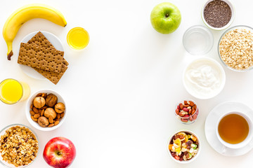 Ingredients for healthy breakfast. Fruits, oatmeal, yogurt, nuts, crispbreads, chia on white background top view copy space