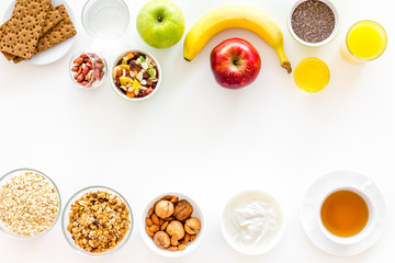 Ingredients for healthy breakfast. Fruits, oatmeal, yogurt, nuts, crispbreads, chia on white background top view copy space