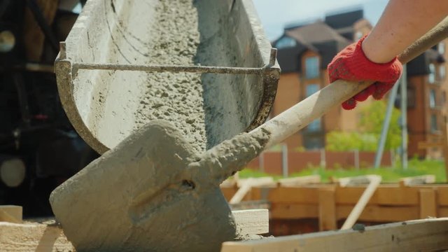 Pour concrete from the mixer into the formwork. In the background, blurred new buildings. Construction of cottages concept
