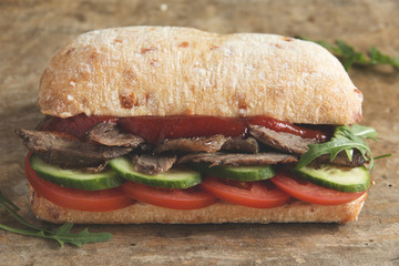 roast beef sandwich with tomato cucumber arugula red sauce