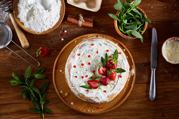 Strawberry tart covered with whipped sour cream surrounded by organic ingredients over wooden background, flat lay.