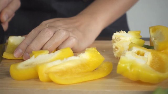 Slow motion - Close up of woman making healthy food and chopping bell pepper on cutting board in the kitchen.