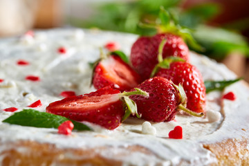 Tart with strawberries and whipped cream decorated with mint leaves on rustic wooden background, selective focus