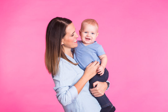happy young mother with a baby child on pink background