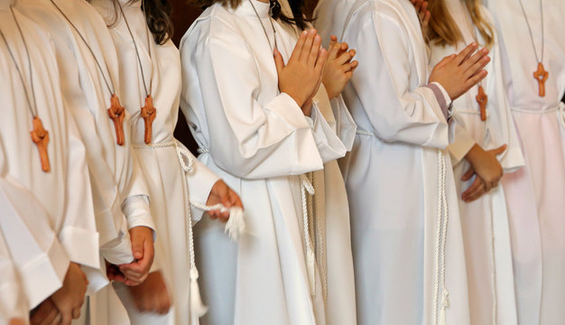 many children with long white tunic during the first communion