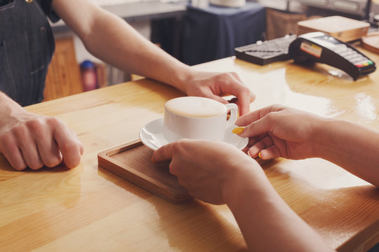 Barista serving coffee cup on wooden bar counter