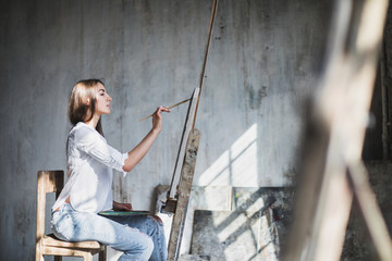 Female artist in studio painting natural lighting.