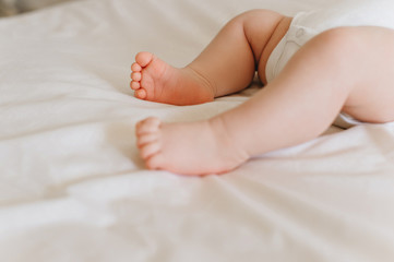 partial view of baby in bodysuit lying on bed