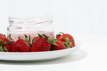 sweet fruit yogurt in a glass jar and fresh strawberries