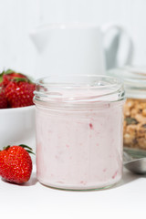 sweet strawberry yogurt, granola and fresh berries on white table, vertical closeup
