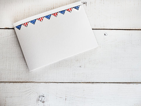 Blank card with a pattern in the form of a US flag on a white, vintage, wooden table. Top view, close-up