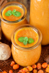 Yellow smoothie with berries of sea buckthorn in glass jars decorated with mint
