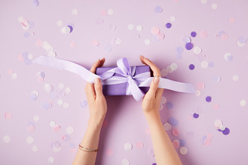 Plakat cropped image of woman holding present box at table with confetti pieces