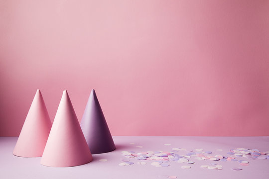 Pink And Violet Party Hats And Confetti Pieces On Violet Surface