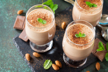 Chocolate-nut mousse close-up with mint in portion glasses on a stone or slate background.