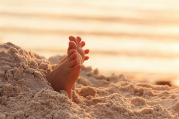 Closeup child kid feet on white sand beach.