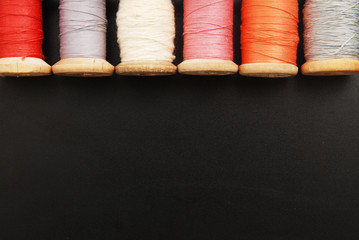 Close up Rolls of Vintage Colorful Threads. Clothes Repair, Black Dark Background. Sewing work process. copy Space.