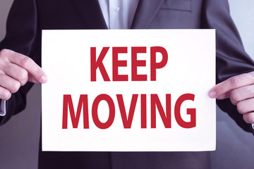 businessman holding paper sheet with Keep Moving text